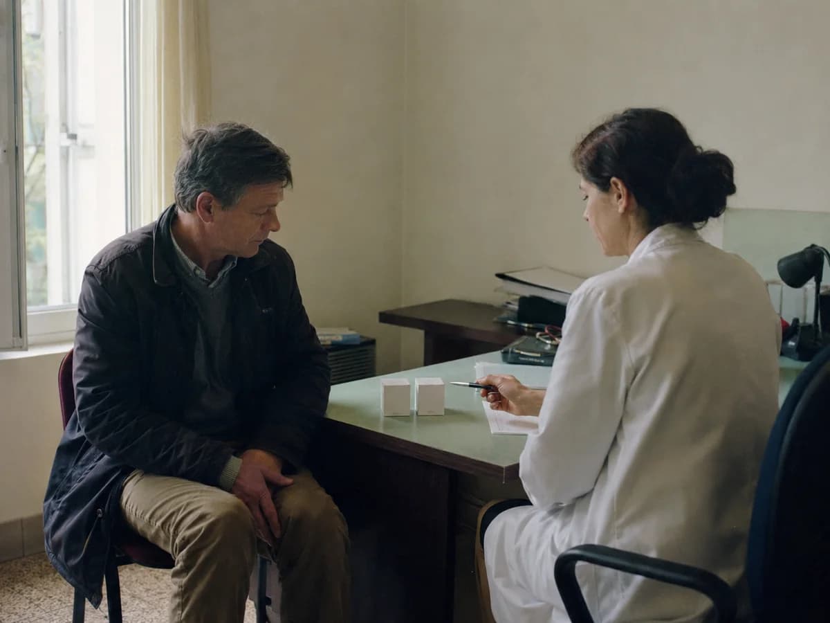 Doctor discussing two unlabelled medicine boxes with a patient in a consulting room